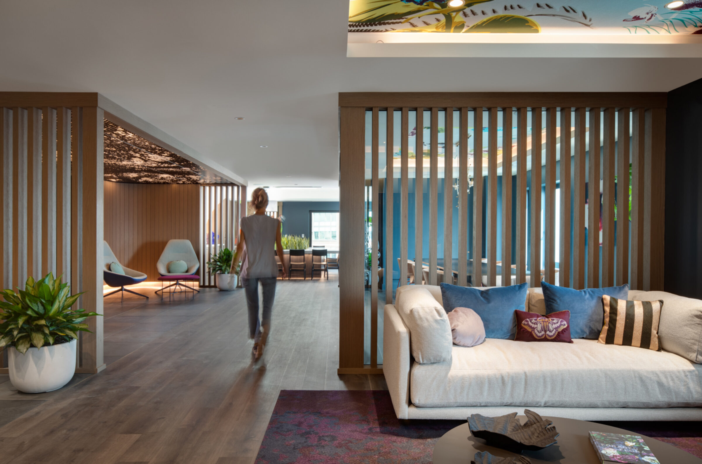 Full view of amenity lounge with a white couch, seating areas in the background and person walking through the space
