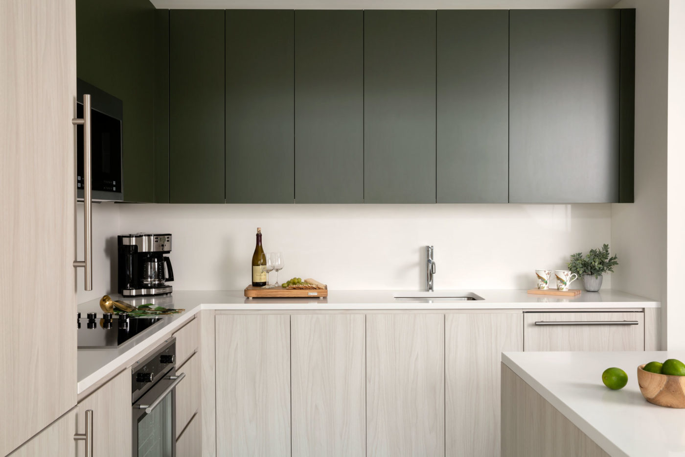 Green and wood cabinets with white countertops and island